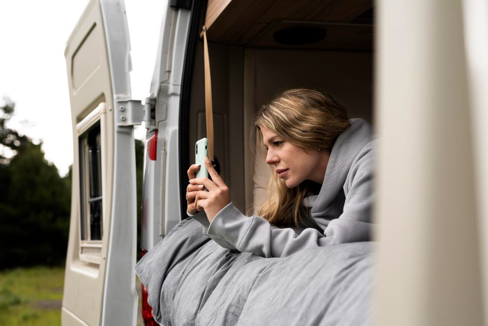 Woman relaxing in a camper van with sunlight streaming in.